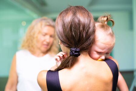 Sad little girl on hands at mum. Woman swears at mom with babyの写真素材