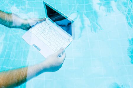 Male hands with a laptop working underwater. The concept of obstruction in the work. Blur Abstract Backgroundの写真素材