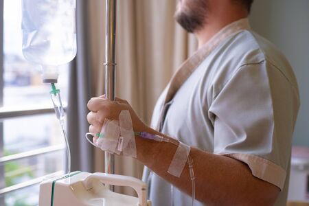 Close-up. patient with a dropper looks out the window of the hospital room and smiles. back view. Healthcare conceptの写真素材