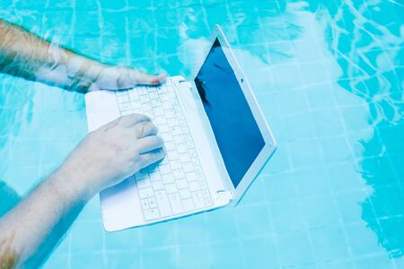 Male hands with a laptop working underwater. The concept of obstruction in the work. Blur Abstract Backgroundの写真素材