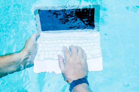 Male hands with a laptop working underwater. The concept of obstruction in the work. Blur Abstract Backgroundの写真素材