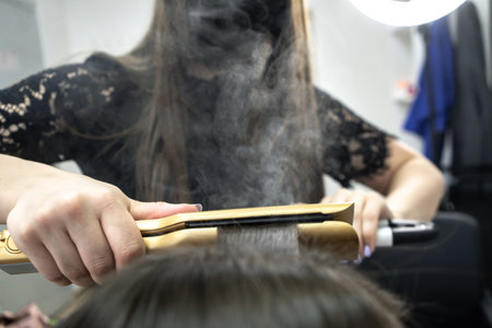 Cute girl with long brunette hair hairdresser doing hair lamination in a beauty salon. concept of hair care treatment. steam from hair.の写真素材
