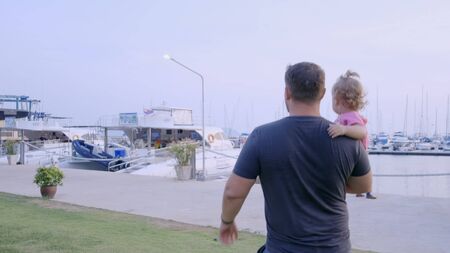 Pattaya, Thailand - May 10, 2019: Dad with a small daughter in his arms go to the marina of the yacht berth and consider the yacht, slow motion, 4kのeditorial素材