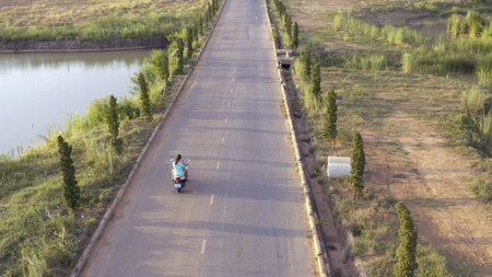 Couple riding motorcycle on rural road. Stock. Top view of riding motorcyclist and his woman....