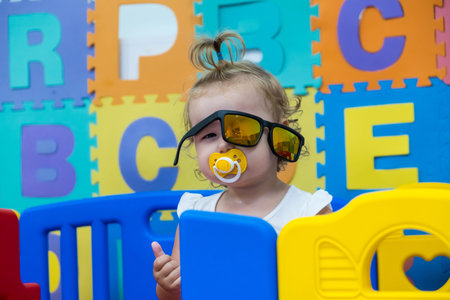 cute little girl plays with toys in the playroom, kindergarten