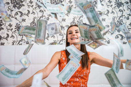 lot of banknotes fly in the air on a girl lying on a white bed in slow motion. Huge wealth of money.の写真素材