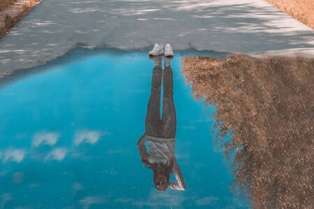 Reflection of a person standing near a puddle. Style is a reflection of your attitude and your personality. The concept of lonelinessの写真素材