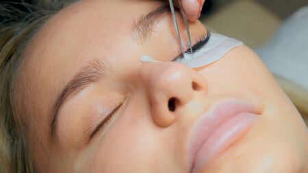 Eyelash removal procedure close up. Beautiful Woman with long lashes in a beauty salon. Eyelash extensionの写真素材