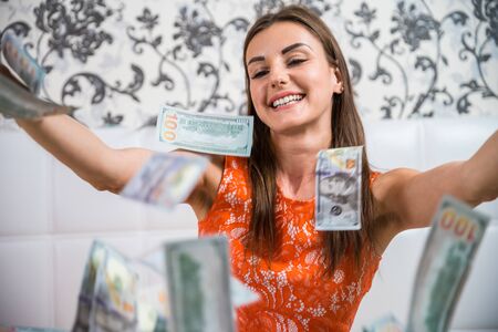 lot of banknotes fly in the air on a girl lying on a white bed in slow motion. Huge wealth of money.の写真素材