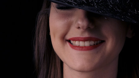 Beautiful sexy woman in a black witch costume with red lips and a hat, looking at the camera and...