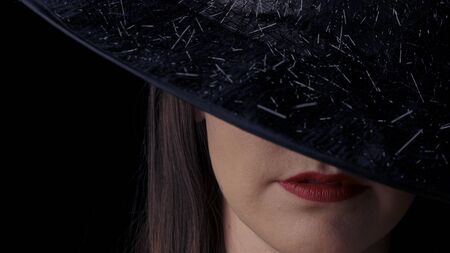 Beautiful sexy woman in a black witch costume with red lips and a hat, looking at the camera and smiling. close-up.の写真素材