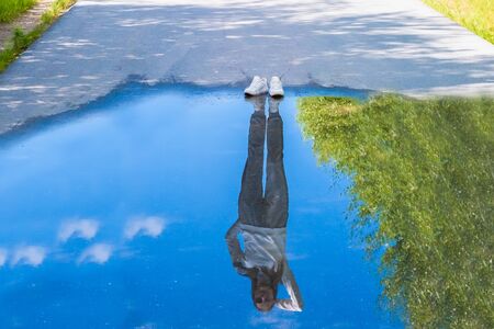 Reflection of a person standing near a puddle. Style is a reflection of your attitude and your personality. The concept of lonelinessの写真素材