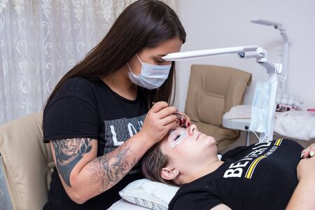 Nizhnevartovsk, Russia - August 12, 2019: eyelash extension master long eyelashes beautiful girl in a beauty salon. Eyelash extension procedureのeditorial素材