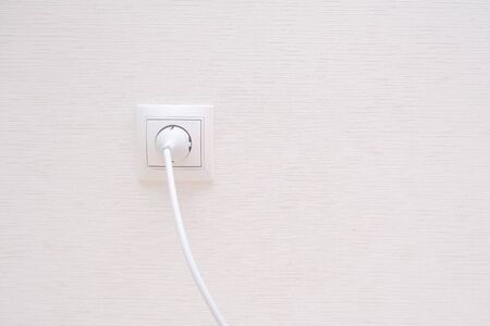 White electrical plug in the electric socket on a wallの写真素材