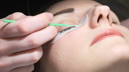 Beauty concept. Eyelash extension process. Master tweezers fake long lashes beautiful female eyesの写真素材