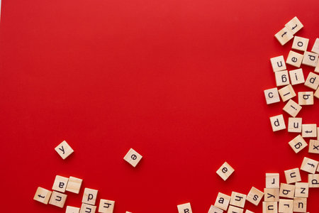 Background image The letters are scattered in disarray. English letters. wooden square letters on bright red background. Greeting card, ready-made layout, selective focusの写真素材