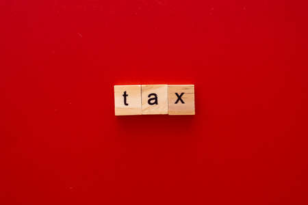 word TAX made of wooden letters on red background with copy space.の写真素材
