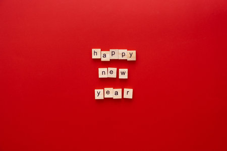 word HAPPY NEW YEAR made of wooden letters on red background with copy space.