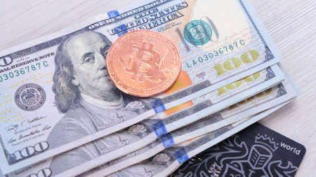 cryptocurrency Bitcoin and a credit card and one hundred dollar bills. BTC blockchain payments, mobile portable storing and payment, paying with crypto currency abstract conceptの写真素材