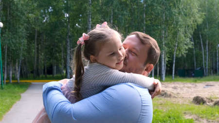 Happy father carrying around his neck and hugging daughter 4-5 years old while walking in the park.の写真素材