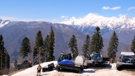 working tractor clears the road from snow on the mountain of the ski resort in Caucasus mountains on...