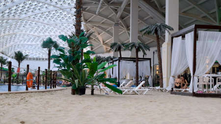 Indoors a luxurious indoor swimming pool with blue water and real golden sand. The concept of summer vacations and recreation, travel, swimming training: Sochi, Russia - May 17, 2021のeditorial素材