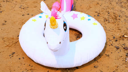inflatable ring in the form of a white Unicorn on the sand on the beach. Fantasy swim ring for summer sailing at sea. Dream concept of summer vacation, sunny day and warm weatherの写真素材