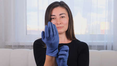 woman puts on blue protective gloves on her hands to prevent bacteria from getting on the skin of the virus epidemic. Protective agent for skin treatments.の写真素材