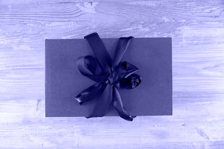 Gift box with a bow on a background with a wooden texture, top view. Very Peri toned image. Place for text.の写真素材