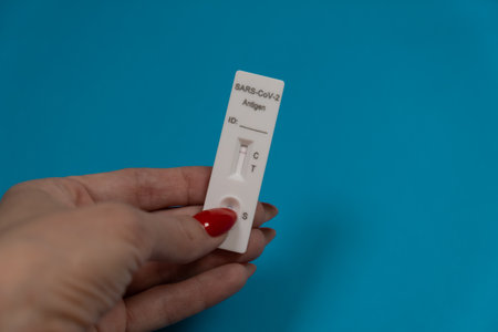 Female hand holding Negative SARS-CoV-2 Rapid Antigen Test on blue background.の写真素材