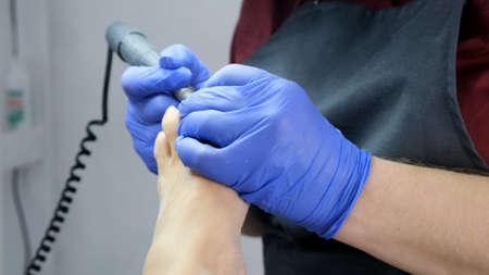 Pedicure SPA procedure in the beauty salon. Peeling feet. Electric apparatus for pedicure. Close up, selective focusの写真素材