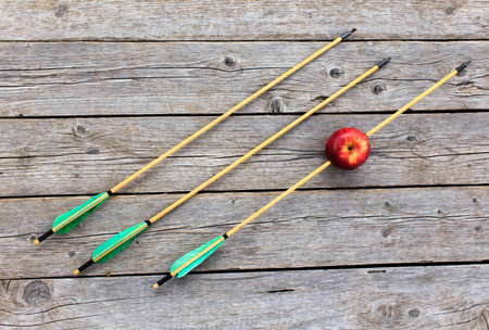 arrow pierced apple. three arrows on wooden background symbolize three attempts to hit the targetの写真素材