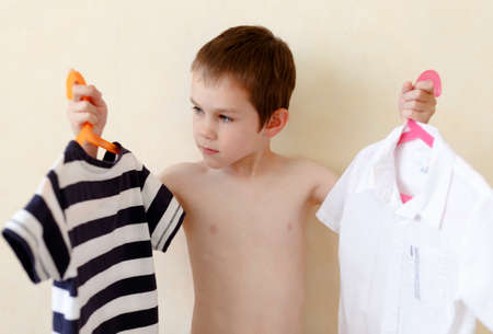 boy chooses clothes. boy chooses between office shirt and a casual t-shirt.boy chooses a profession, conceptの写真素材