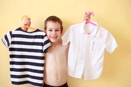 boy trying on clothes. the boy buys his clothes: shirt and t-shirtの写真素材