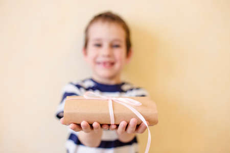 child holds out a gift. the child gives a gift tied with a ribbonの写真素材