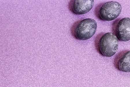 Eggs with marble stone effect painted with natural dye carcade flower on lilac sparkling backgroundの写真素材
