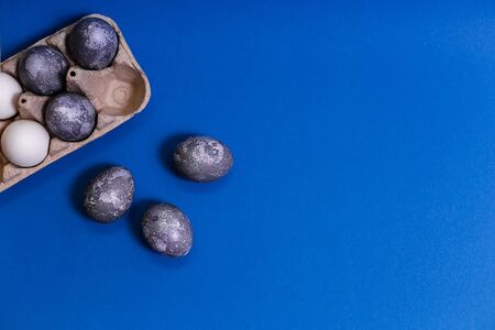 Eggs with marble stone effect painted with natural dye carcade flower on blue sparkling backgroundの写真素材