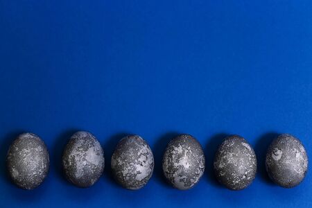 Eggs with marble stone effect painted with natural dye carcade flower on blue sparkling backgroundの写真素材