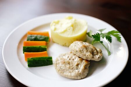 Meanced meat cotlets with mashed potatoes and fresh vegetables on the wooden table. Front view. Children menu.の写真素材