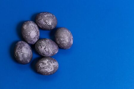 Easter card. Eggs with marble stone effect painted with natural dye carcade flower on blue sparkling background with blank space for text. Top view. Flat layの写真素材