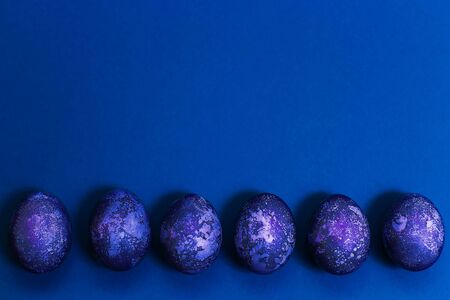 Easter card. Eggs with marble stone blue effect painted with natural dye carcade flower on blue sparkling background with blank space for text. Top view. Flat layの写真素材