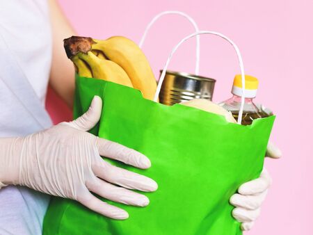 Food delivery. Hands in gloves. Coronavirus, COVID 19. Paper bag with eco foodの写真素材