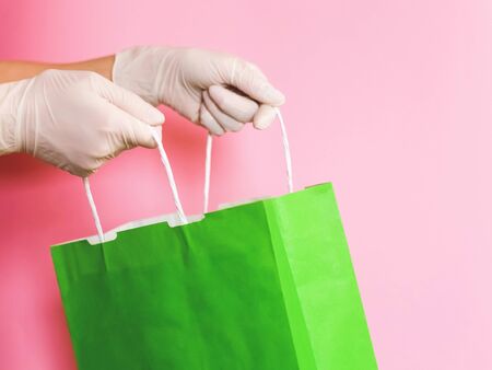 Consumer pack product. Delivery. Hand in a glove holds a green craft package with handles.の写真素材