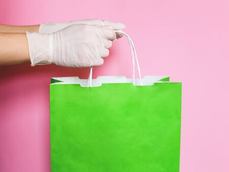 Consumer pack product. Delivery. Hand in a glove holds a green craft package with handles.の写真素材