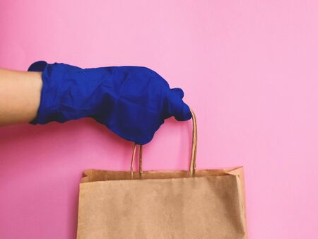 Consumer pack product. Delivery. Hand in a glove holds a brown craft package with handles.の写真素材