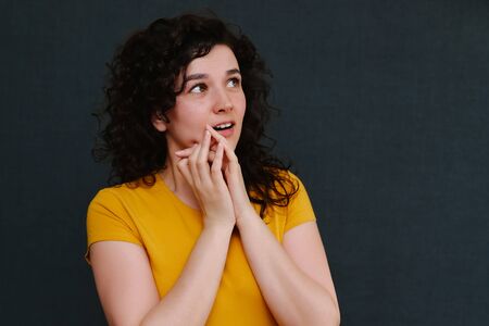 Portrait of funny emotional curly girl on grey background. Surprise. Joy. Happy.の写真素材