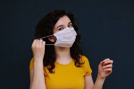 A woman taking off a medical mask and laughing on the grey background. The end of epidemic. The end of coronavirus.の写真素材