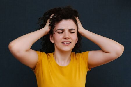 Portrait of funny emotional curly girl on grey background,thinking about something. Upset. Pain. Fright. Sadness. Copy spaceの写真素材