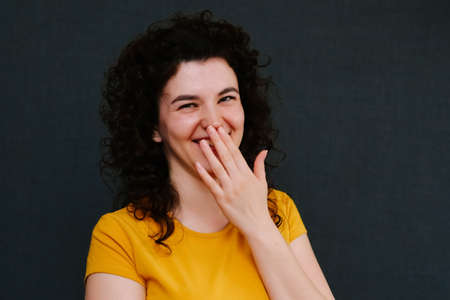 Portrait of funny emotional laughing curly girl, on grey background. Surprise. Joy. Happy. Copy spaceの写真素材