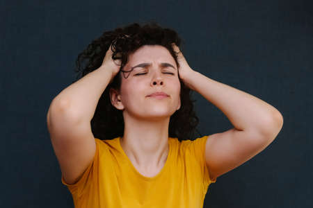 Young charismatic caucasian woman showing pain on her face on the grey background.の写真素材